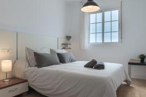 a white bedroom with a large bed with a window at AT Tino Casal in Almería