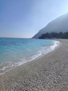 a beach with blue water and a rocky shore at Babahouse in Camerano