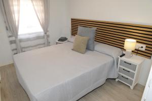 a bedroom with a large white bed with a wooden headboard at La coqueta in Murcia
