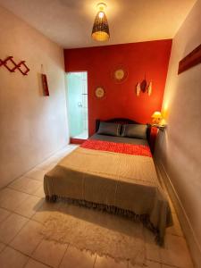 um quarto com uma cama numa parede vermelha em La Casita Hostel PF na Praia do Forte