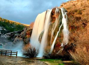 a waterfall on a hill with a bench in front of it at Apartment ZORA in Knin