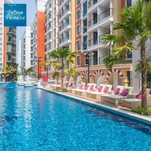 uma piscina com palmeiras e edifícios em Espana Resort Jomtien Beach Pattaya em Praia de Jomtien