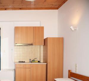 uma cozinha com armários de madeira e um lavatório em Elena Rooms em Áyios Nikítas