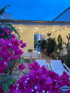 un patio con fiori viola e tavoli e sedie bianchi di Suite Battisti 7 a Lecce