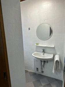 La salle de bains blanche est pourvue d'un lavabo et d'un miroir. dans l'établissement Hotel Gambrinus, à Pachten