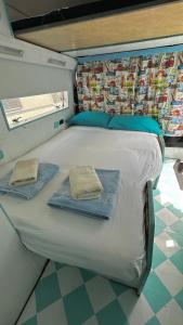 łóżko w pokoju z dwoma ręcznikami w obiekcie Autocaravana Dory w Lizbonie