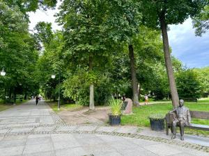 a statue of a man sitting on a park bench at CitizenA Studio no smoking in Radom