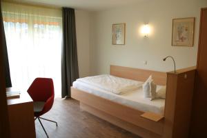 a bedroom with a bed and a desk and a window at Hotel-Restaurant Bellevue in Ruhpolding