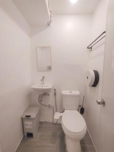 a white bathroom with a toilet and a sink at VG Pension & Residences in Adlawon