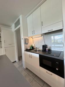 Una cocina con gabinetes blancos y un fregadero. en LuganoLake, en Bissone