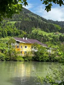 uma casa amarela ao lado de um rio em Appartement Christine em Sankt Johann im Pongau