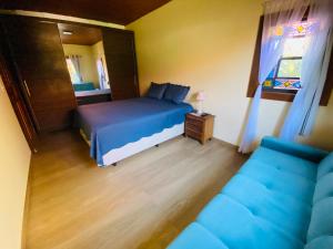 um quarto com uma cama azul e um sofá em “Recanto Pingo de Ouro” em Tiradentes