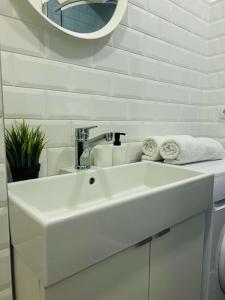 a white sink in a bathroom with a mirror at Milastos apartamentai in Birštonas