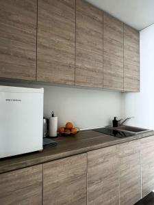 a kitchen with a sink and wooden cabinets at Milastos apartamentai in Birštonas