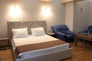 a bedroom with a bed and a blue chair at Sofiivs'ka apartments in Kyiv