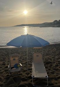 two chairs and an umbrella on the beach at A due passi dal mare in Castiglioncello