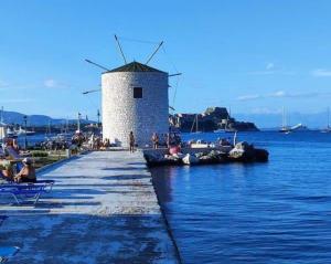 a dock with a windmill in the middle of the water at Villa Maxim in Corfu Town in Anemómylos