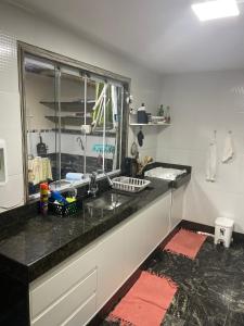 eine Küchentheke mit einem Waschbecken und einem Fenster in der Unterkunft Casa pé na areia - Brandão House in Saco dos Cações