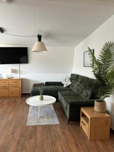 Stadtapartment KUS في كلاغنفورت: غرفة معيشة مع أريكة خضراء وطاولة