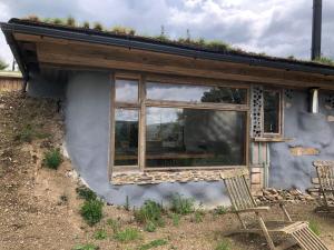 South Brent的住宿－Rabbits 1or 2 bedroom hobbit style hillset earthen dartmoor eco home，一座带窗户的建筑,有草屋顶