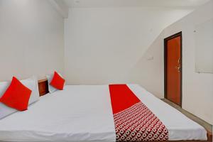 1 dormitorio con cama blanca y almohadas rojas en OYO Flagship City Light Hotel en Kānpur