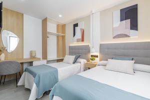1 dormitorio con 2 camas, mesa y escritorio en Stay Belonio, en Málaga