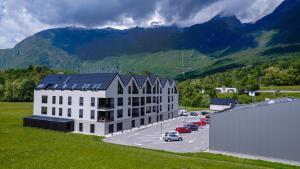 un grand bâtiment blanc avec des voitures garées dans un parking dans l'établissement Charming Bovec Apartment, à Bovec