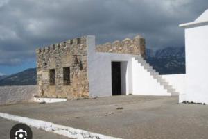 a white building with a door and stairs on a street at house FYNTIKAKH - SKALA in Anopoli Sfakion