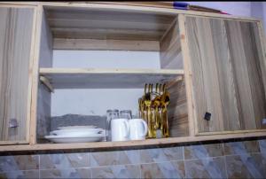 a wooden cabinet with plates and utensils in it at Floviol home in Mombasa