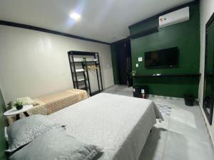 a bedroom with two beds and a green wall at Pousada Point in Aracati