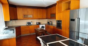 una cucina con armadi in legno e frigorifero in acciaio inossidabile di Villa Casa Brandao a Póvoa de Varzim