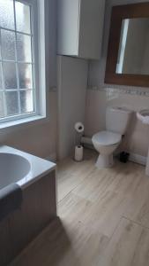 ein Bad mit einer Badewanne, einem WC und einem Fenster in der Unterkunft Alexander Apartments Heaton in Heaton