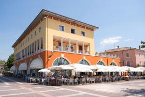 un edificio con tavoli e ombrelloni bianchi di fronte ad esso di Hotel Vela D'oro ***S a Bardolino