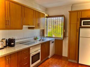 a kitchen with wooden cabinets and a sink and a window at Buenos Sueños- Balcon de Frigiliana in Frigiliana