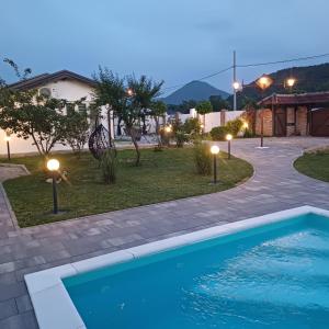 a swimming pool in front of a house with lights at Family estate Hadžalova avlija in Bihać