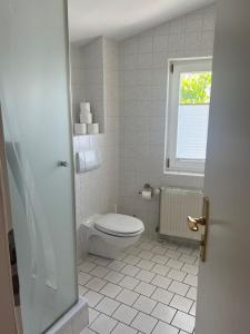a white bathroom with a toilet and a window at Fährblick - Pension direkt am Wasser in Sassnitz