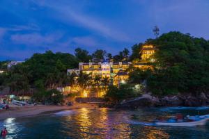 a hotel on a hill next to a beach at night at Hotel Casa Justina in Puerto Ángel