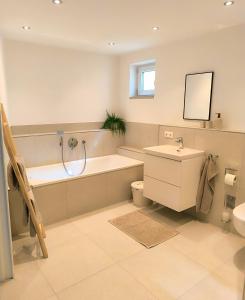 a bathroom with a tub and a toilet and a sink at Ferienwohnung Niederbuchner in Chieming