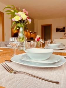 a table with plates and bowls and a vase of flowers at Landhaus Sonnrain Fendels in Fendels