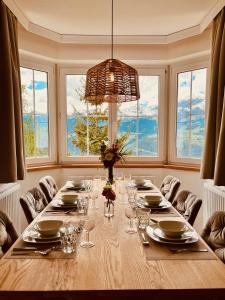 a dining room with a long table and windows at Landhaus Sonnrain Fendels in Fendels