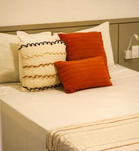 uma cama com almofadas cor-de-laranja e brancas em Fontes da Pipa by Liiv Rooms em Pipa