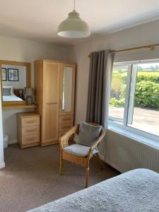 um quarto com uma cadeira e uma janela em Leylands Annexe em East Harptree