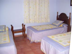 Habitación con 2 camas y una silla. en Casa Concha, en Almadén de la Plata