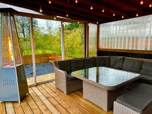 Un porche cubierto con una mesa de cristal y un sofá. en Lincontournable - Jaccuzi-Piscine-Sauna-Hammam, en Challans