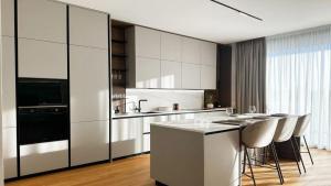 a kitchen with white cabinets and a island with bar stools at Ferienwohnung Olympiastadion APT DELUXE in Berlin