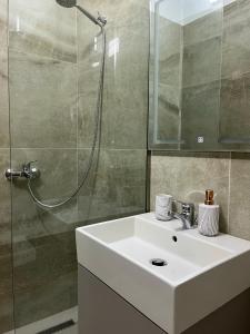 a bathroom with a white sink and a shower at Lotus Apartments in Vlorë +120 photos