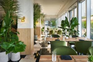um restaurante com mesas de madeira e cadeiras e plantas verdes em W Miami em Miami