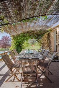 a patio with a table and chairs under a pergola at L'Arbre d'Alice in Ongles