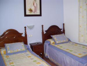 a bedroom with two beds and a night stand at Casa Concha in Almadén de la Plata