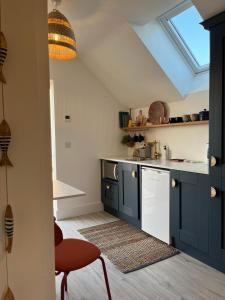 una cocina con armarios azules y una silla roja en The Loft Curracloe, on Wexfords Coastal Scenic Route, en Wexford